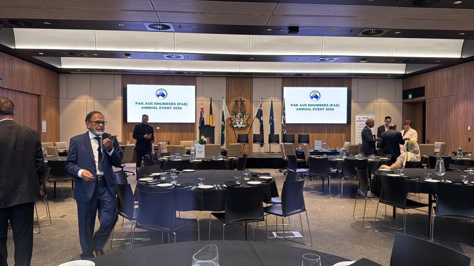 The Council Chamber set for the PAK AUS Engineers Annual Event 2025, with the Association's name on the screens and its banner beside the stage